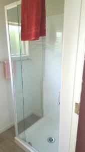 a glass shower in a bathroom with a red towel at Jacks place in Moeraki