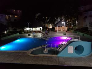 a swimming pool at night with purple and blue at ROSI Ocean Sand Hotel Apt (@Sandcastles) in Ocho Rios