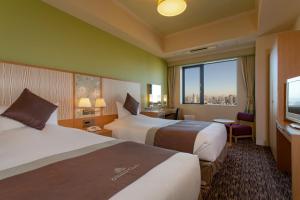 Cette chambre comprend deux lits et une grande fenêtre. dans l'établissement Hotel Monterey Grasmere Osaka, à Osaka