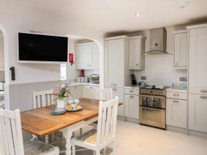 a kitchen with a wooden table and a television on the wall at Offshore in Porthtowan +16 photos