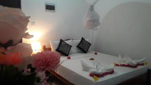 - une chambre dotée d'un lit blanc avec des oreillers et des fleurs noirs dans l'établissement Dream Villa Sigiriya, à Sigirîya