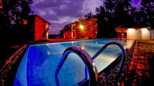 una piscina por la noche con las luces encendidas en Amri River Cottages And Ayurvedee Retreat, en Bentota