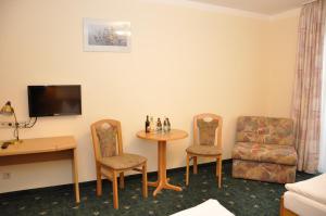 ein Hotelzimmer mit einem Tisch, Stühlen und einem Schreibtisch in der Unterkunft Waldhotel Hubertus in Eisfeld