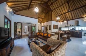 sala de estar amplia con sofás y cocina en Axros Villa, en Ubud