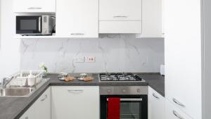 una cucina con mobili bianchi e un forno a piano cottura di Mgarr Waterfront Cosy Apartment 2 by Ghajnsielem Gozo a Mġarr