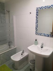 La salle de bains blanche est pourvue d'un lavabo et de toilettes. dans l'établissement Apartamentos Chevere Azul, à Oviedo