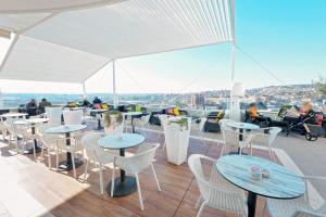 a rooftop patio with tables and chairs and a view at Jolly Hotel in Lezhë