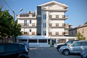 a tall white building with cars parked in a parking lot at La Lanterna in Silvi Marina
