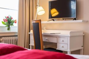a bedroom with a desk with a tv and a bed at Residenz Seeterrasse Restaurant & Hotel in Wangen