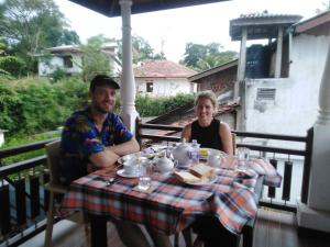 un homme et une femme assis à une table sur une terrasse couverte dans l'établissement Janu Homestay, à Tangalle