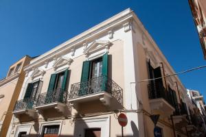 a white building with green shutters and a balcony at Dimora Apulia in Brindisi