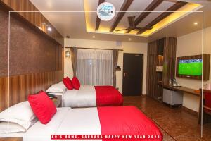 een hotelkamer met 2 bedden en een televisie bij KC's Home in Sauraha