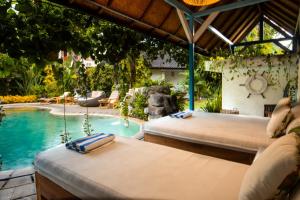 two beds in a room with a swimming pool at Sanur House in Sanur