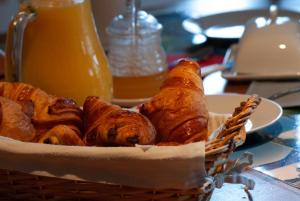 uma cesta de croissants e outros produtos de pastelaria sobre a mesa em Maison d'hôtes La Colombelle em Colombé-le-Sec