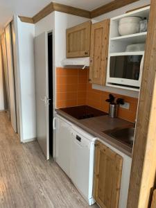 eine kleine Küche mit Holzschränken und einem Waschbecken in der Unterkunft Studio Chalets de Solaise in Val dʼIsère