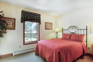 a bedroom with a bed with a red blanket and a window at Oro Grande in Keystone