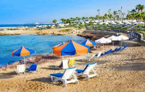 a group of chairs and umbrellas on a beach at The Paphos Pafia 2 Apartment in Paphos