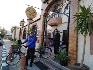 達哈布的住宿－TheCastle Hotel，两个人站在建筑物外,骑着自行车
