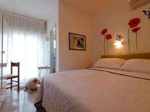 een slaapkamer met een wit bed en rode bloemen aan de muur bij Kristalex Pet Family Hotel in Cesenatico