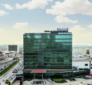 um edifício de escritórios de vidro alto com uma auto-estrada movimentada em Ankara Alegria Business Hotel em Ancara