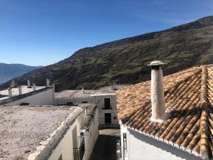 a view of roofs of buildings and a mountain at Hotel Rural Real de Poqueira in Capileira