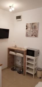 a room with a desk with two stools and a television at Studio Apartment Legcevic in Kaštela