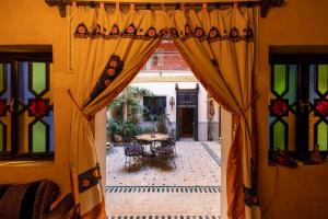 een open deur naar een patio met een tafel en stoelen bij RIAD MAKENE MOUCHKILL in Marrakesh