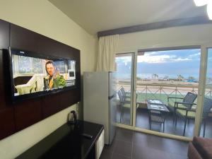 Pokój z balkonem i telewizorem z płaskim ekranem. w obiekcie Porto South Beach Royal Sea view families صف اول بحر مباشر w mieście Ajn Suchna