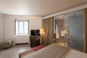 a bedroom with a bed and a television and a window at Memmo Alfama - Design Hotels in Lisbon