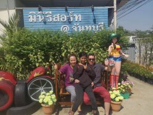 un grupo de personas sentadas en un banco con una chica en MiniResort Chanthaburi, en Chanthaburi