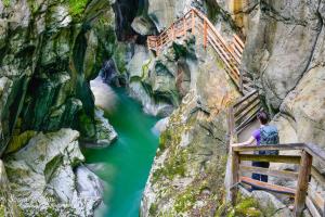 un hombre parado en un puente de madera sobre un río en Ferienhaus Niederl en Golling an der Salzach