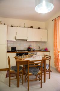 una cucina con tavolo e sedie e una cucina con armadietti bianchi di Casa Vacanze Soledad a Marina di Ragusa