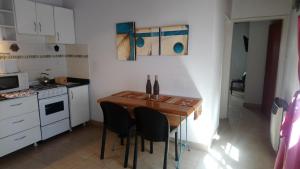 Il comprend une petite cuisine avec une table et des chaises en bois. dans l'établissement Departamento Ananda, à General Roca