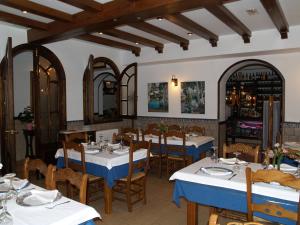 um restaurante com mesas brancas e cadeiras com toalhas de mesa azuis em Caico's em Prado del Rey