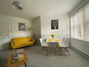 a living room with a table and a yellow couch at ONE BEDROOM FLAT IN FULHAM in London