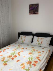 a bed with a floral comforter and two pillows at 19 RESIDENCE apartment in Cavnic