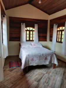 a bedroom with a bed and two windows at Recanto casa amarela in Miguel Pereira