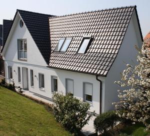 une maison blanche avec un toit noir dans l'établissement FeWo Blankenese im Haus Lühegarten, à Grünendeich