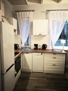 uma cozinha com armários brancos e um lavatório em Apartments by the beach em Trzebiez
