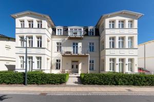 ein großes weißes Haus mit Büschen davor in der Unterkunft Villa Quisisana in Ahlbeck