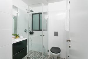 a white bathroom with a shower and a toilet at Mr. Brooklyn - By TLV2GO in Tel Aviv