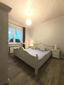 een slaapkamer met een wit bed en een raam bij Apartments by the beach in Trzebież