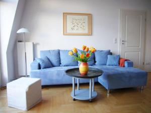 ein Wohnzimmer mit einem blauen Sofa und einem Tisch mit Blumen in der Unterkunft Villa Quisisana in Ahlbeck