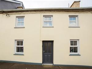 a white house with a black door and windows at Belmullet Townhouse in Belmullet
