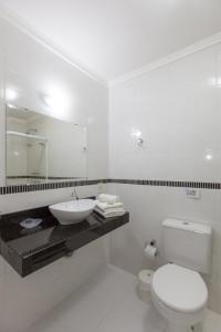 uma casa de banho branca com um lavatório e um WC em Pousada Oásis de Mariscal em Bombinhas