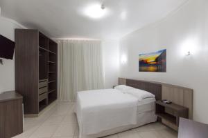 um quarto com uma cama e uma televisão em Pousada Oásis de Mariscal em Bombinhas