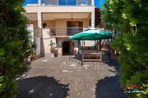 a house with an umbrella and a table and chairs at Villa Dell'Artista Fronte Spiaggia - SiciliaVacanza in Avola