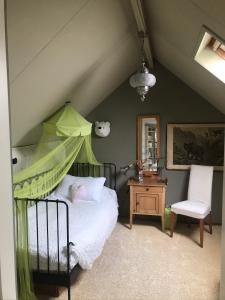 1 dormitorio con 1 cama con dosel verde en B&B De Koraal en Emmen