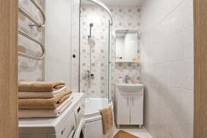 a white bathroom with a shower and a sink at PaulMarie Apartments on Mira 25B in Mogilev