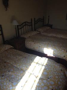 Dos camas en un dormitorio con el sol brillando sobre ellas en Finca la sutilas, en Zahara de la Sierra